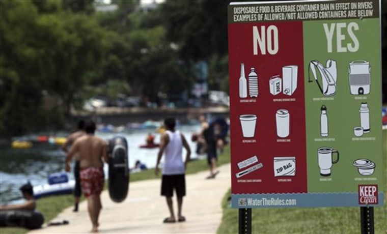 In a May 28, 2012 photo, a sign informs Memorial Day visitors to Prince Solms Park in New Braunfels,Texas, what is acceptable for tubers to carry down the Comal river. Drinking beer while lazily floating through New Braunfels is a heat-beating tradition for hundreds of thousands of vacationers each summer, but turnout is down and businesses say the reason is clear: a new ban on disposable containers. The so-called can ban doesn’t prohibit alcohol, but that message hasn’t been sticking.  (AP Photo/San Antonio Express-News, John Davenport) MAGS OUT NO SALES SAN ANTONIO OUT